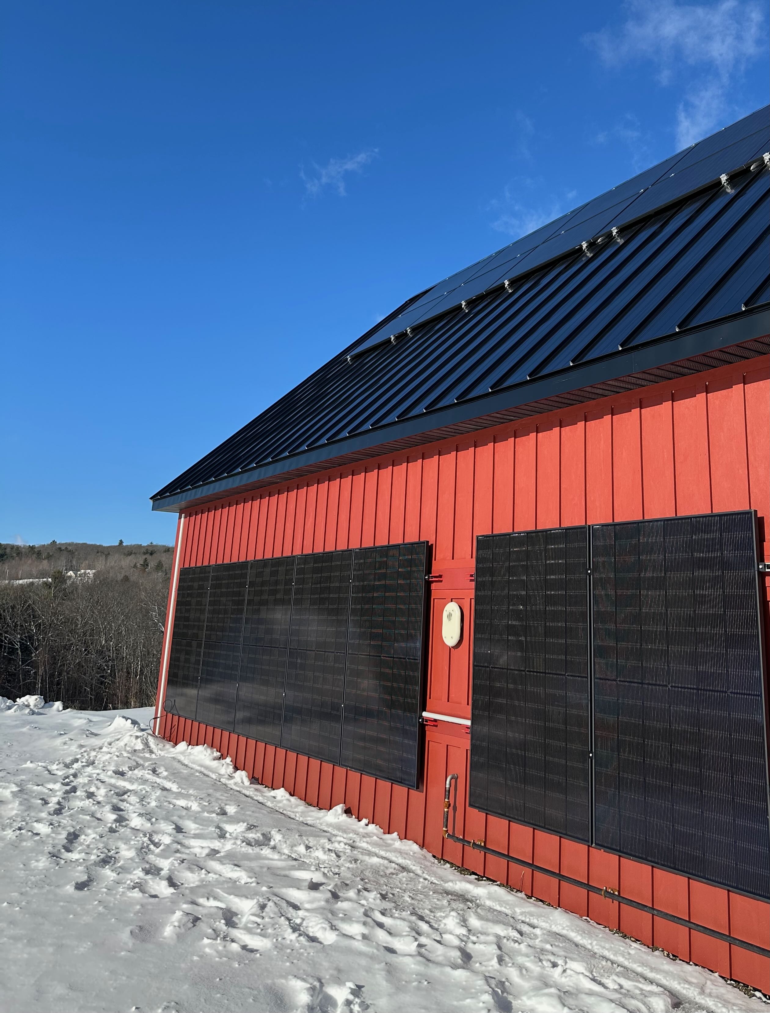 Vertical solar panels on the red studio building in snow
